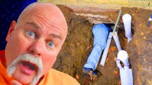 Professional plumber repairing an underground sewer or drain line in an excavation during a residential plumbing repair